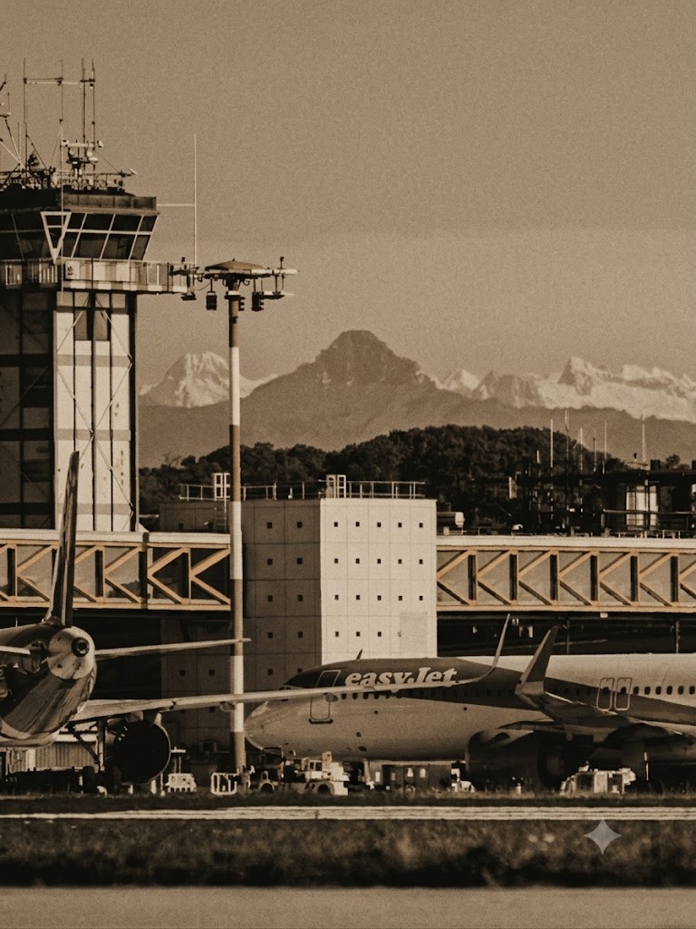 Torre di controllo dell'aeroporto di Milano Malpensa con le Alpi innevate sullo sfondo.