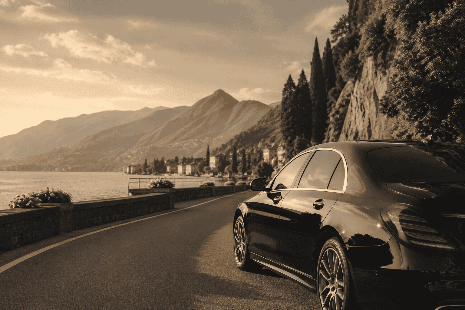 Black Mercedes driving along a lake road.
